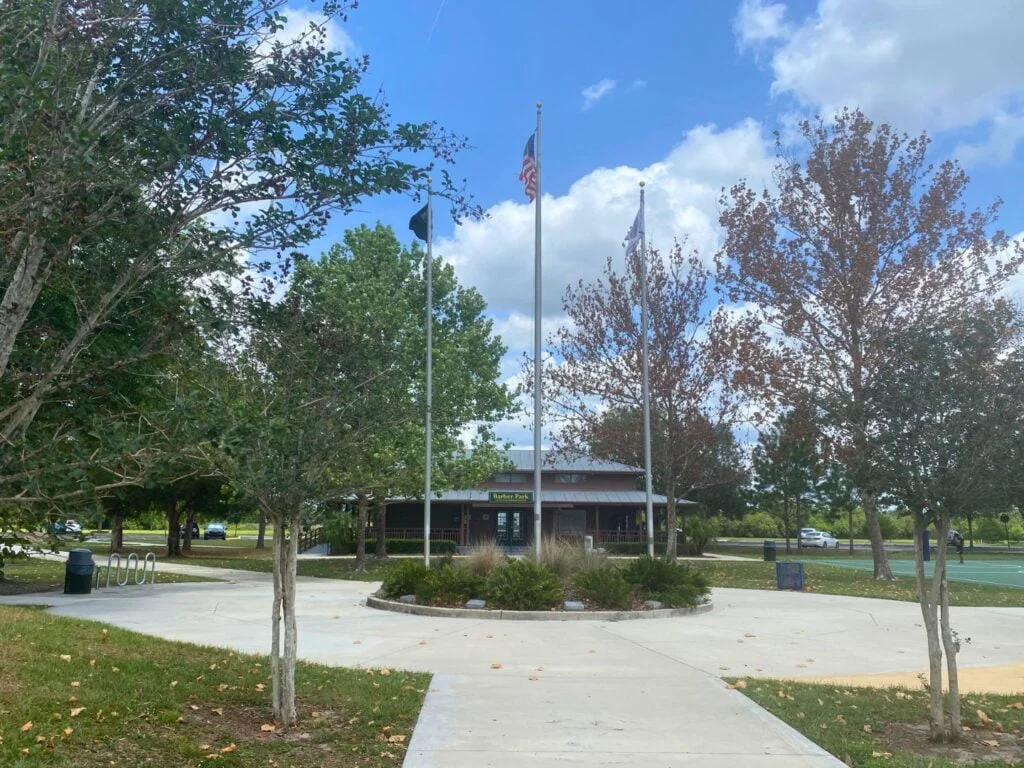 Barber Park entrance with flag poles pavilion and tree-lined pathways in Orlando Florida