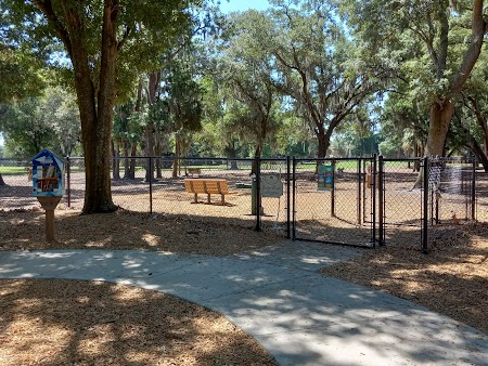 Meadow Woods Dog Park fenced off-leash area with oak trees and benches in Orlando Florida