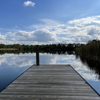 Young Pine Community Park scenic lake dock with cloud reflections in Orlando Florida